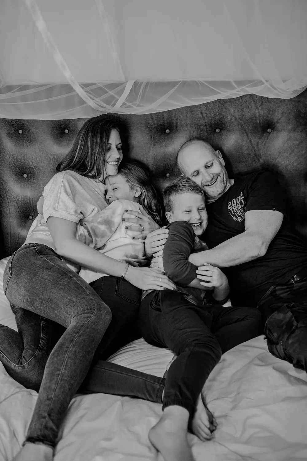 A family cuddled together on a bed, laughing