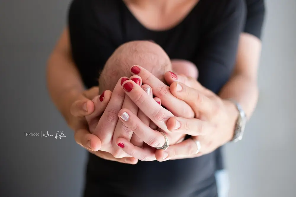 A newborn cradled in hands